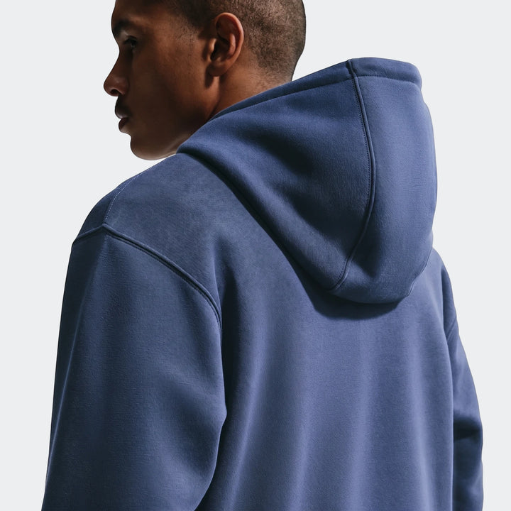 Close-up of a man wearing an England Club blue Men's Nike Soccer Pullover Hoodie, viewed from the back and right profile.