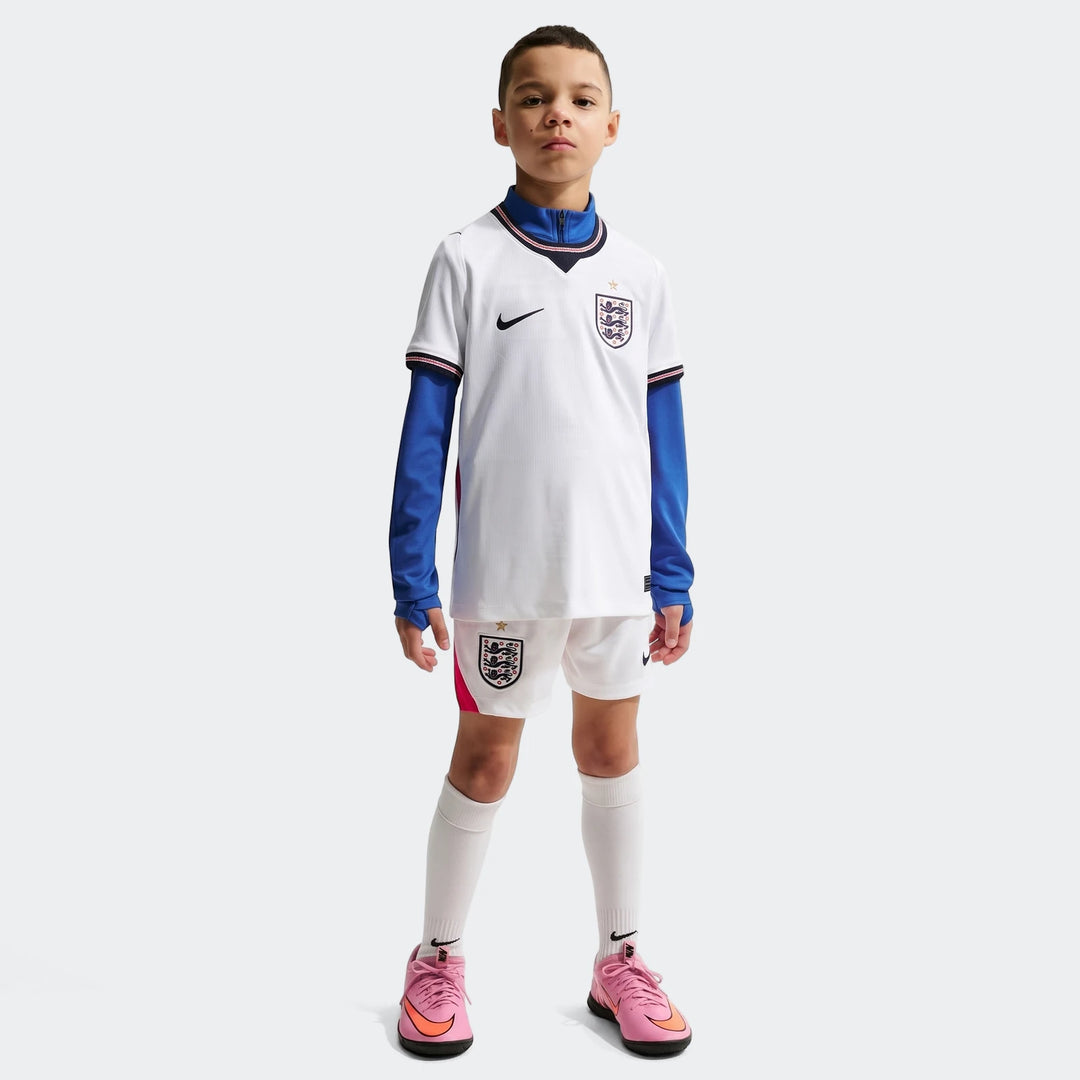 Young boy wearing white England National Team 2026 Stadium Home Nike Dri-Fit soccer jersey, white shorts, and pink shoes.