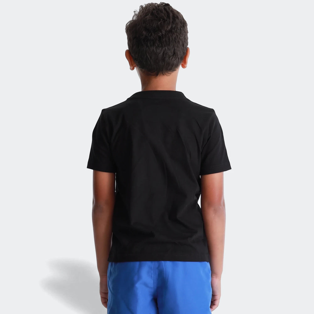 A young boy seen from behind, wearing a black Ess Logo Tee G t-shirt and blue shorts on a white background.