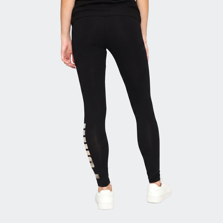 Black Ess Metallic Leggings for women, featuring a metallic stripe detail on the left leg, worn by a model in a full-body