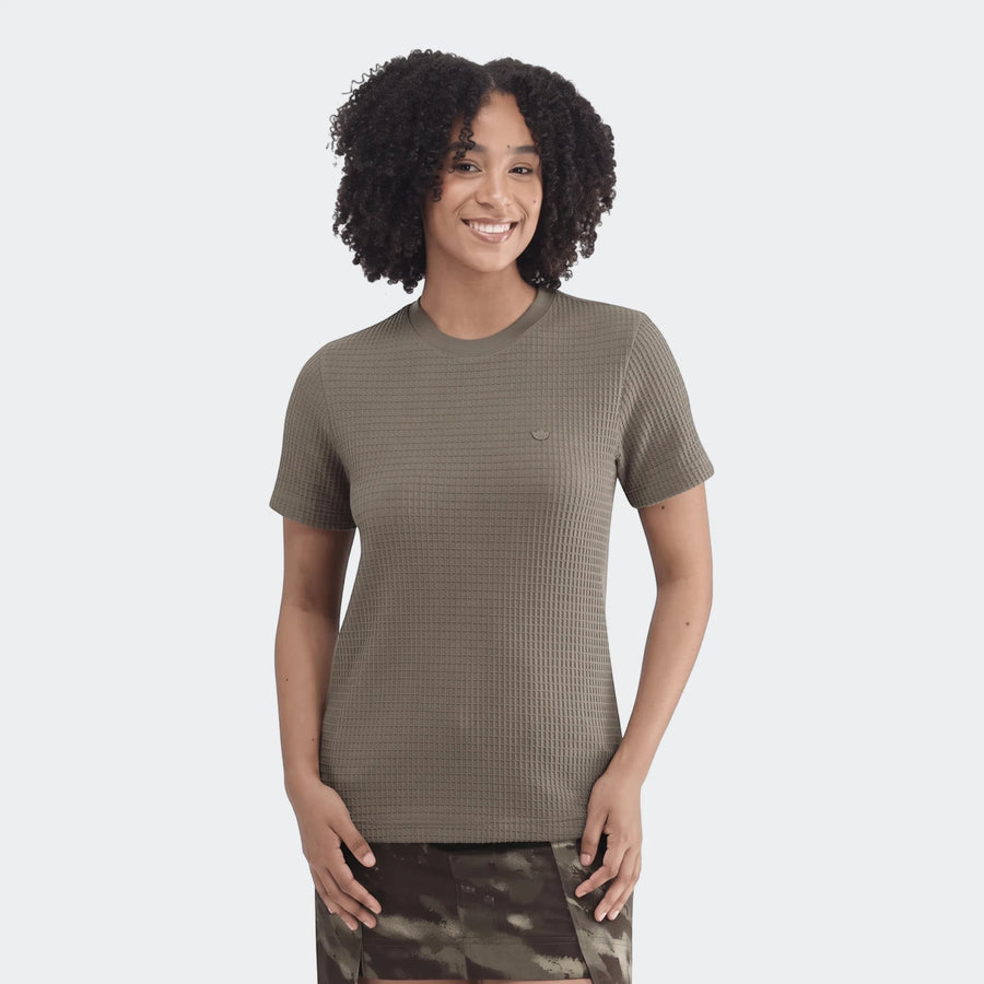 Olive green waffle knit Essential T-Shirt worn by a smiling woman with curly hair, paired with a camouflage skirt.