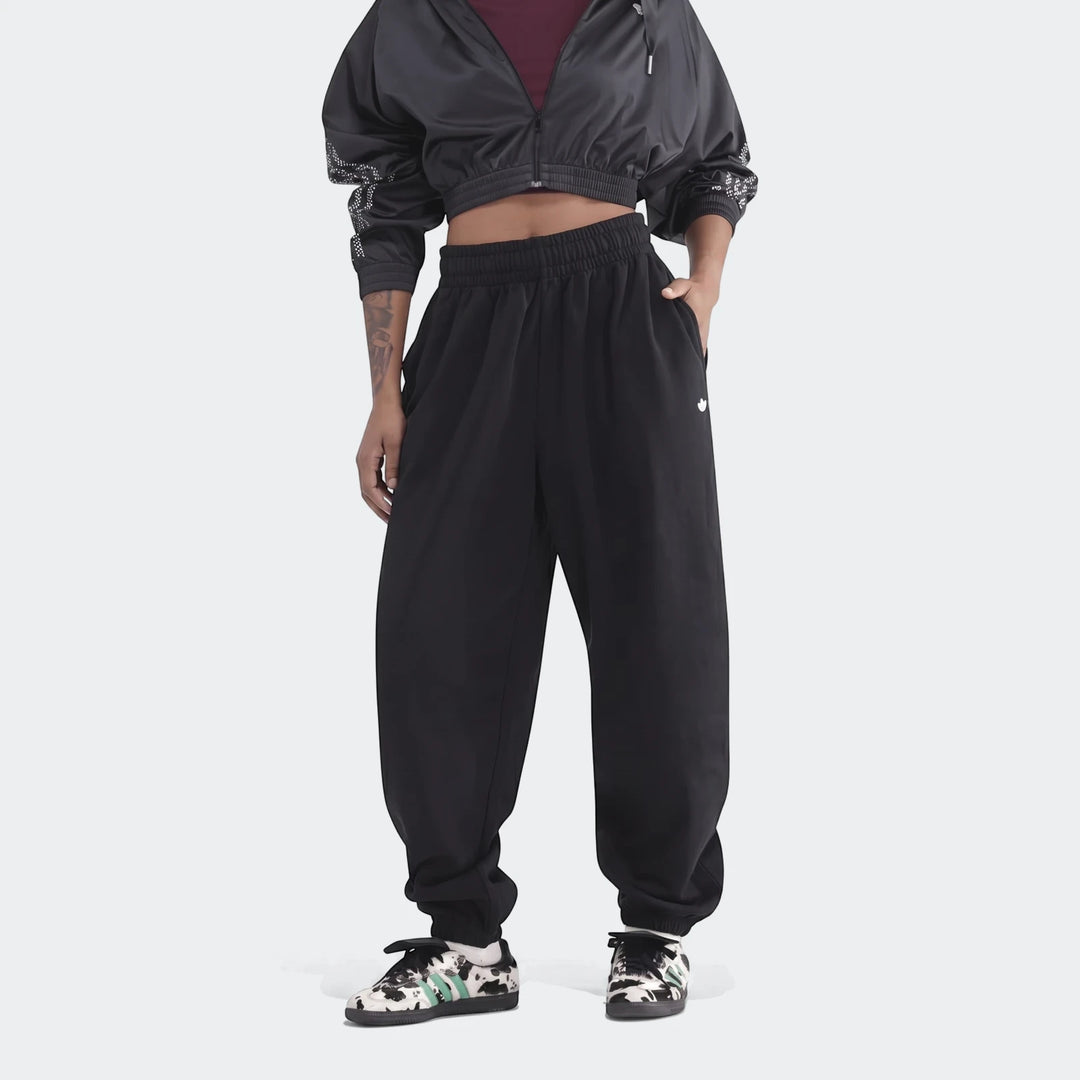 Full body view of a model wearing black Essentials French Terry Jogger Pants and a black cropped jacket with patterned