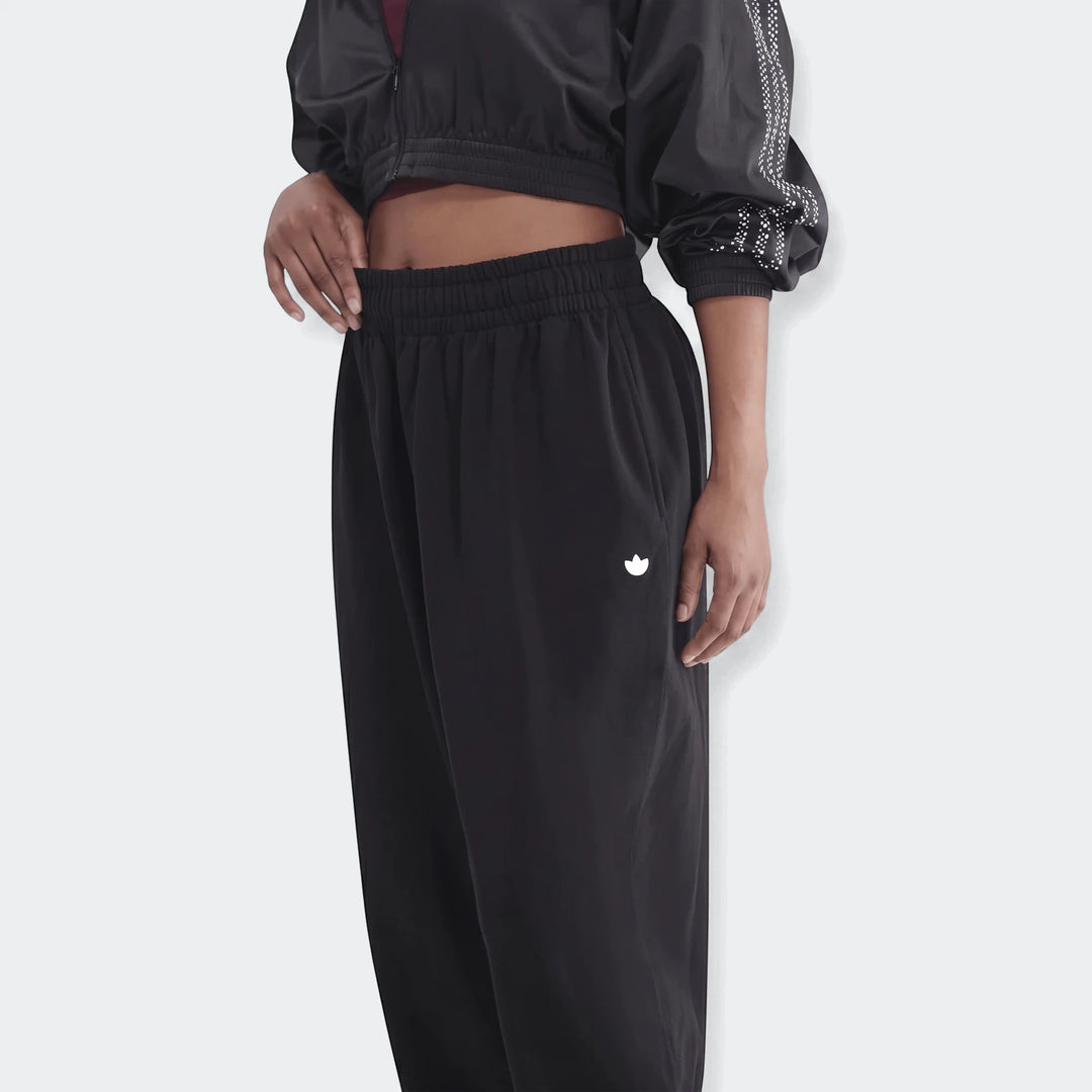Model wearing black Essentials French Terry Jogger Pants and a cropped jacket, showcasing the white logo on the thigh.