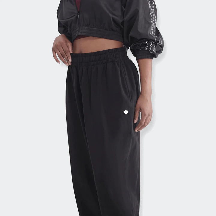 Model wearing black Essentials French Terry Jogger Pants and a cropped jacket, showcasing the white logo on the thigh.