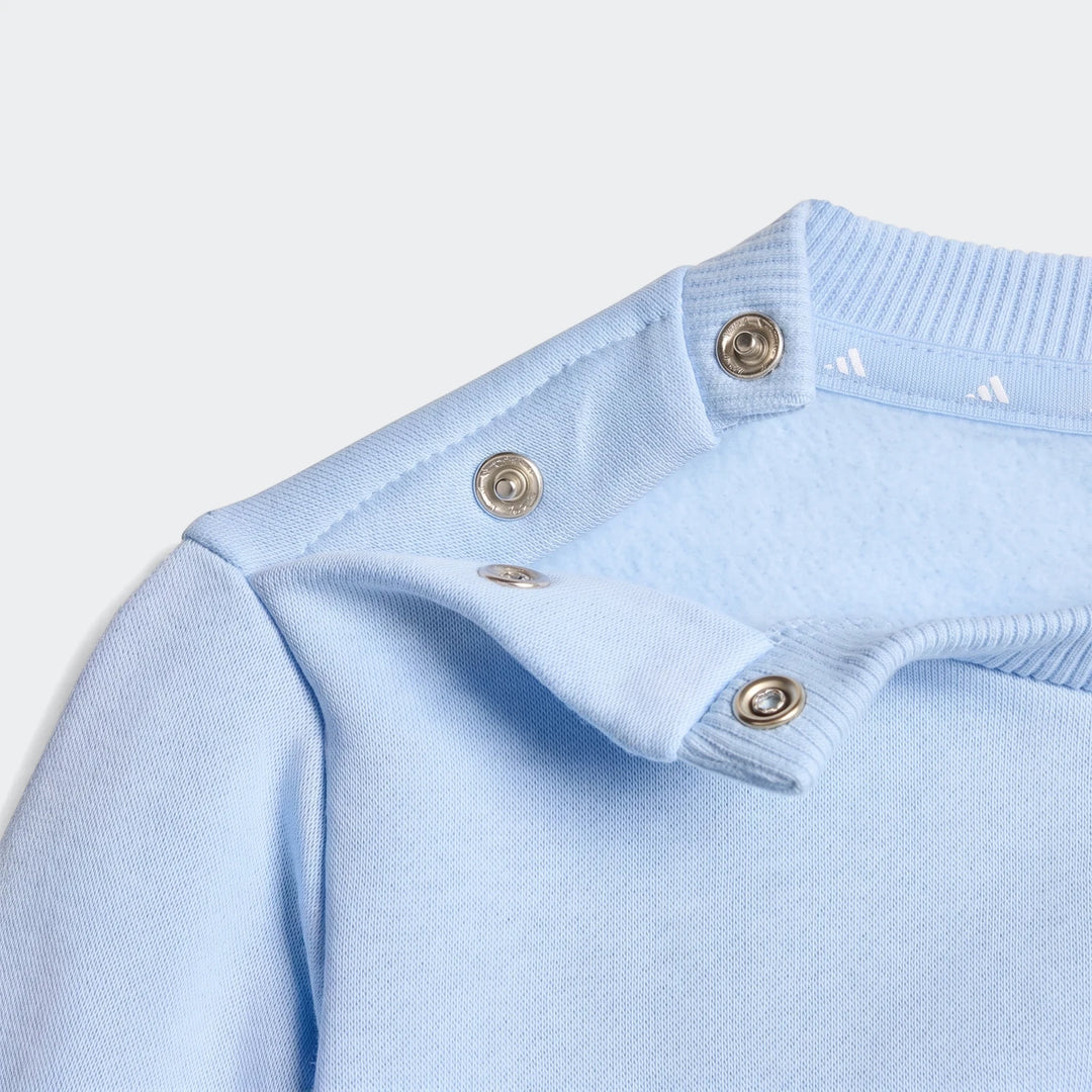 Close-up of a light blue Essentials Jogger Set sweatshirt, highlighting the shoulder with snap buttons and rib-knit collar