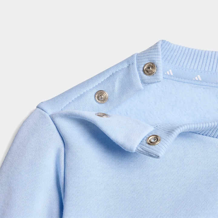 Close-up of a light blue Essentials Jogger Set sweatshirt, highlighting the shoulder with snap buttons and rib-knit collar