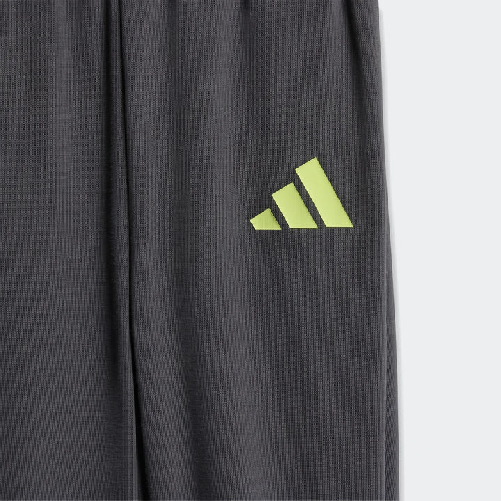 Close-up of a dark grey knit jogger from the Essentials Joggers Set Kids, featuring a bright yellow-green Adidas logo on the