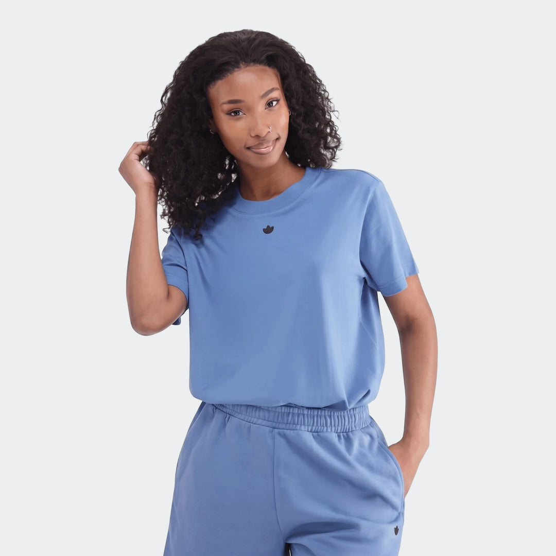 Woman models a blue Essentials Trefoil T-Shirt and matching shorts, showcasing the casual cotton set.