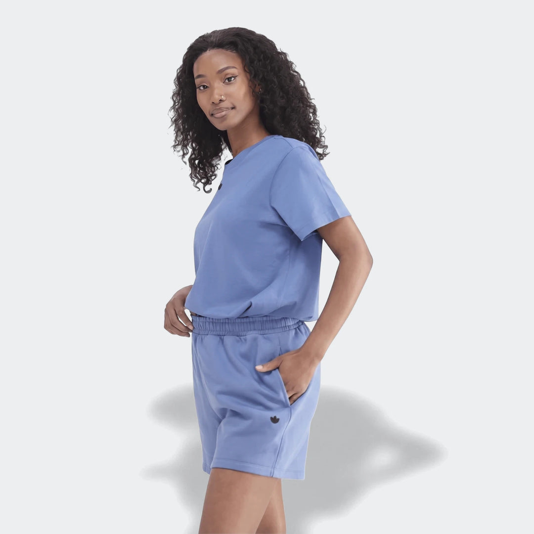Woman wearing a blue Essentials Trefoil T-Shirt and matching shorts, looking confidently at the camera.