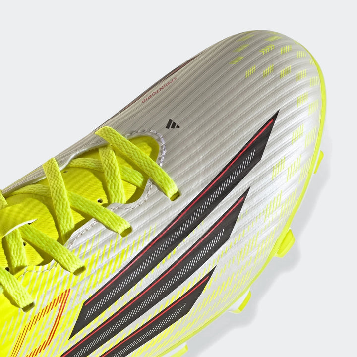 Close-up of white, yellow, and black Adidas F50 Club Firm Ground football boot with neon yellow laces and stripes.