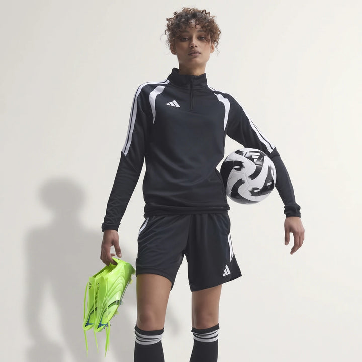 Female model in black Adidas F50 Elite Fg Tunit Football Boots, black sportswear, holding a football.
