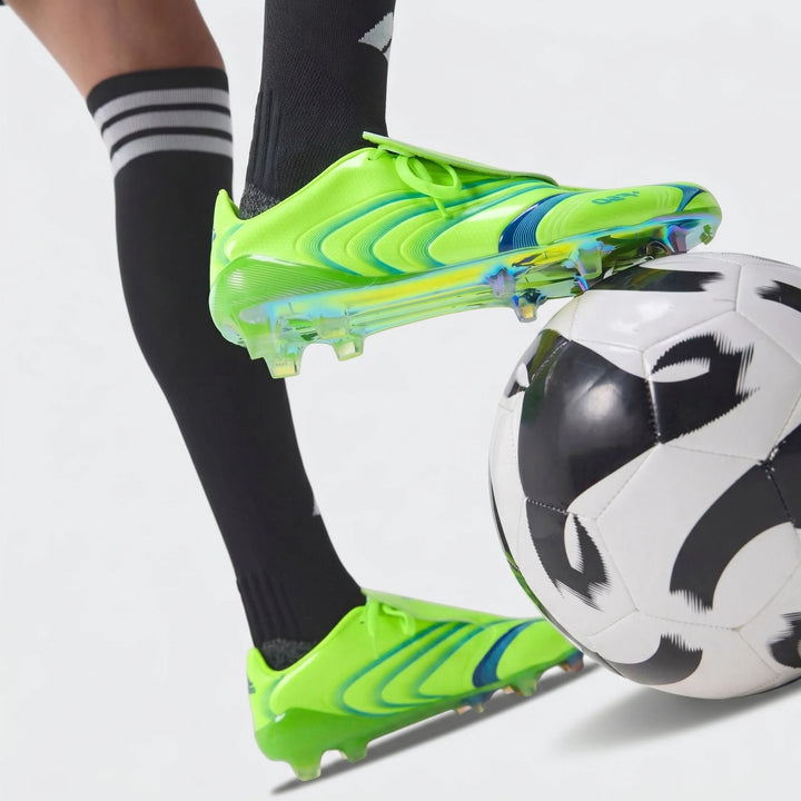 Vibrant green F50 Elite Fg Tunit Football Boots on a player's foot resting on a black and white football.