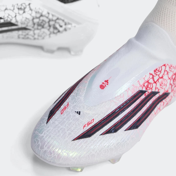 Close-up view of white Adidas F50 Elite LL FG Lamine Yamal football boots with vibrant red floral patterns.
