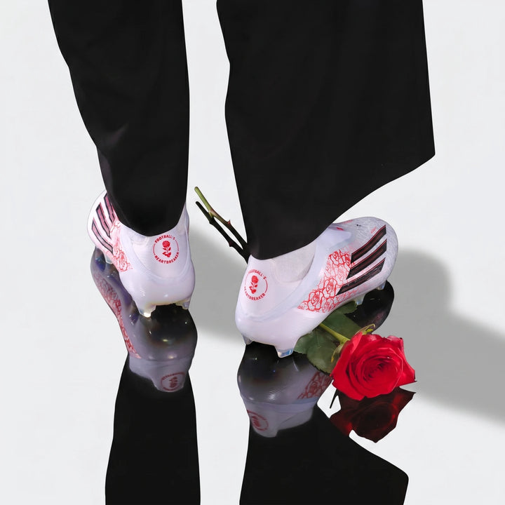 White F50 Elite Ll Fg Lamine Yamal football boots with red rose graphics, worn by a person on a dark reflective surface.