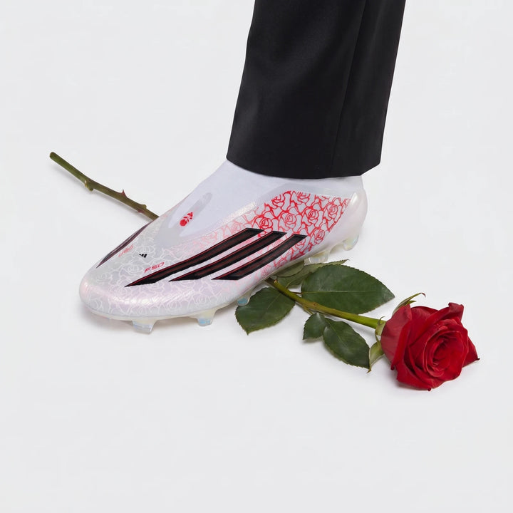 White Adidas F50 Elite Ll Fg Lamine Yamal football boot with red rose pattern and black stripes, next to a red rose.