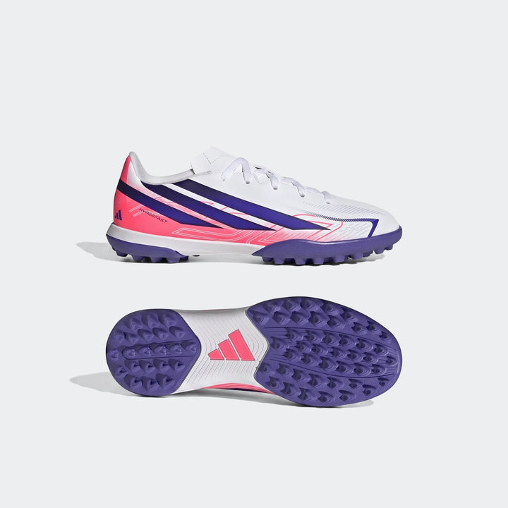 Kids' Adidas F50 Hyperfast Club turf football boots in white, vivid pink, and purple, shown in a side and sole view.