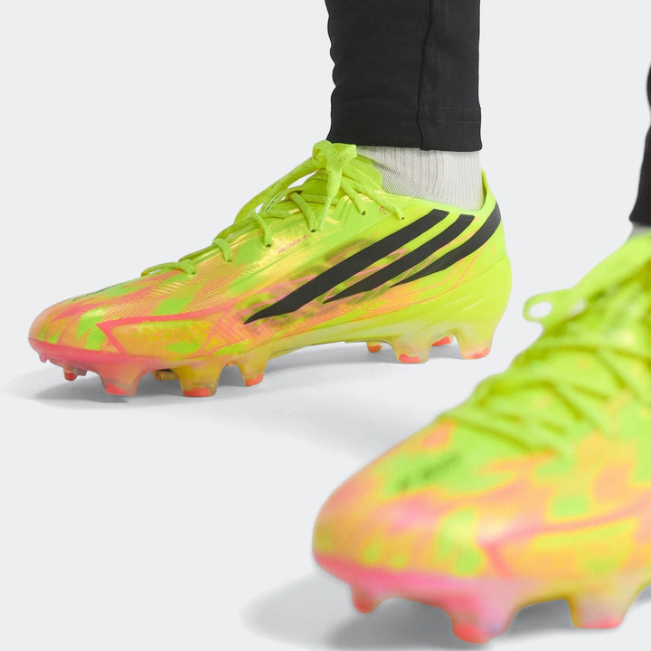 F50 Hyperfast Elite Firm Ground Football Boots in vibrant neon yellow and pink with black stripes, worn on feet, front view.