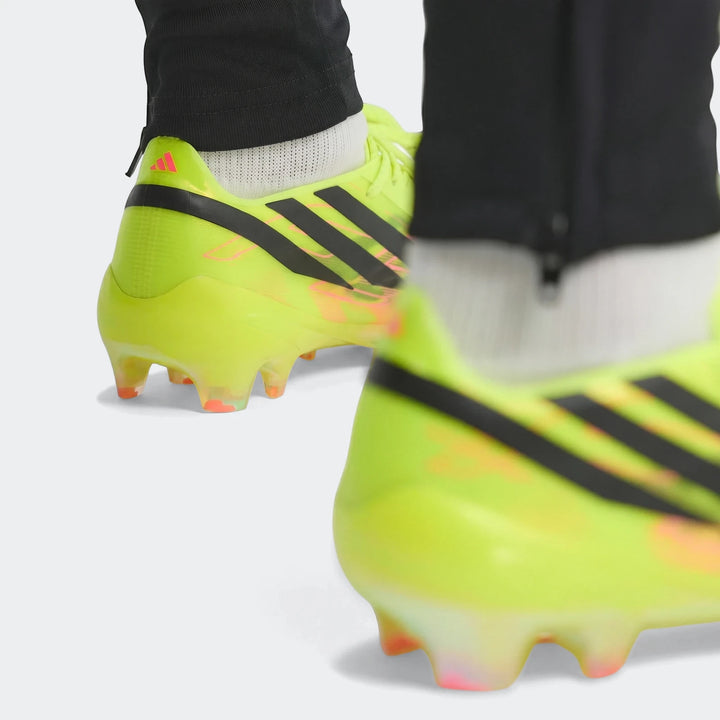 F50 Hyperfast Elite Firm Ground Football Boots in neon yellow, featuring black stripes and pink accents, worn for play.