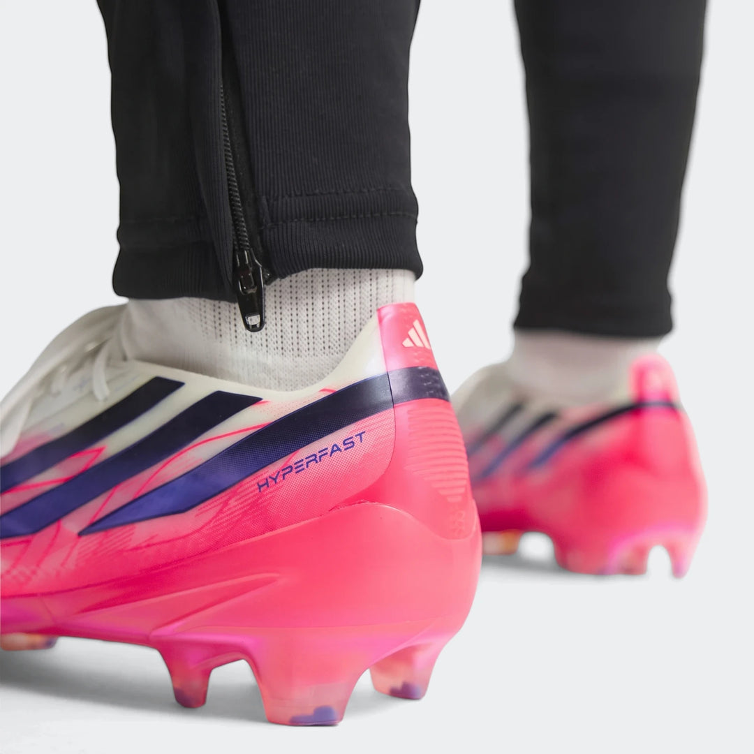 F50 Hyperfast Elite Firm Ground Football Boots in vibrant pink, white, and purple worn by a player, rear view.