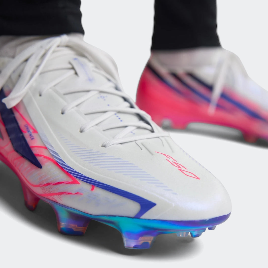 Close-up of F50 Hyperfast Elite Firm Ground Football Boots in white, pink, and blue, showcasing the iridescent studs.