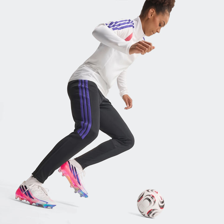 Female athlete in white, pink, blue, and yellow F50 Hyperfast Elite Firm Ground Football Boots with black and purple