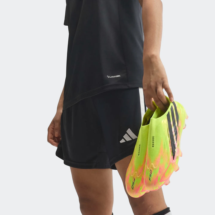 Close-up of a person holding a pair of F50 Hyperfast Elite Laceless Firm Ground Boots in vibrant neon yellow and pink.