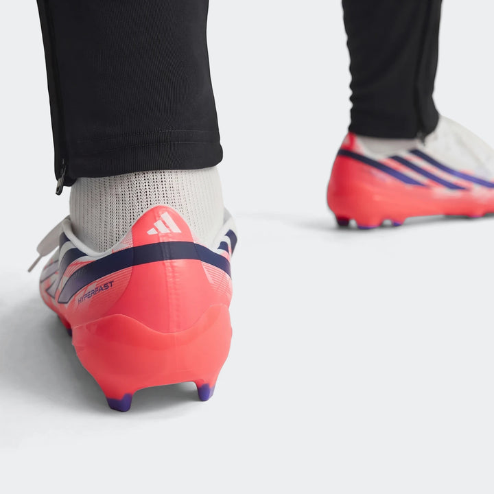 Close-up of white F50 Hyperfast League Firm Ground Football Boots featuring pink soles, dark blue stripes, and a 'HYPERFAST'