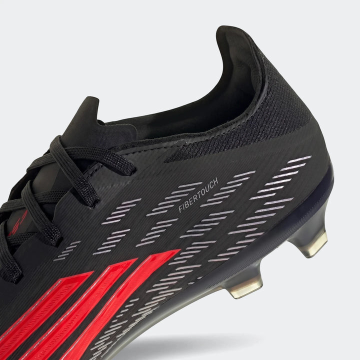 Close-up of a black and red Adidas F50 Pro Firm Ground Football Boot, showing the side view with 'FIBERTOUCH' text.