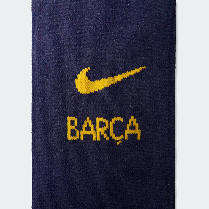 Close-up of a dark blue Nike soccer replica kit fabric with a yellow Nike swoosh logo and BARÇA text.
