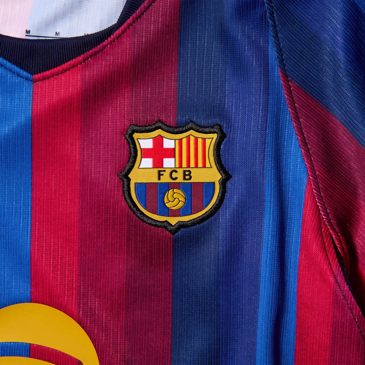 Close-up of a little kids' FC Barcelona 2026 Stadium Home Nike soccer replica jersey, featuring blue and red stripes and the