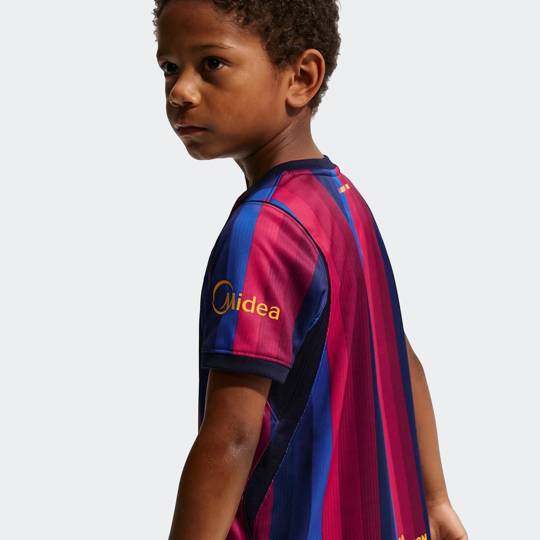 Young boy in FC Barcelona 2026 Stadium Home Little Kids' Nike Soccer Replica 3-Piece Kit, back/side view, blue and magenta