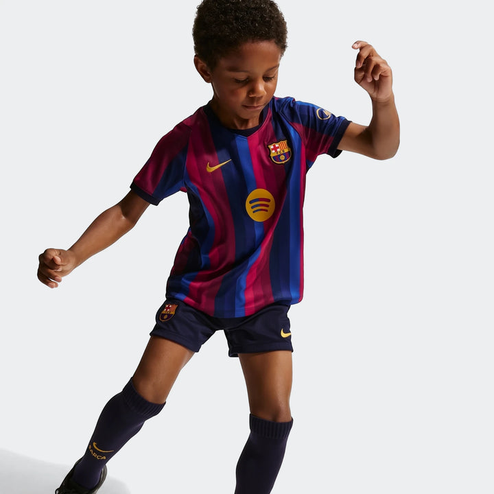 Young boy models the blue and maroon striped FC Barcelona 2026 Stadium Home Little Kids' Nike Soccer Replica 3-Piece Kit.