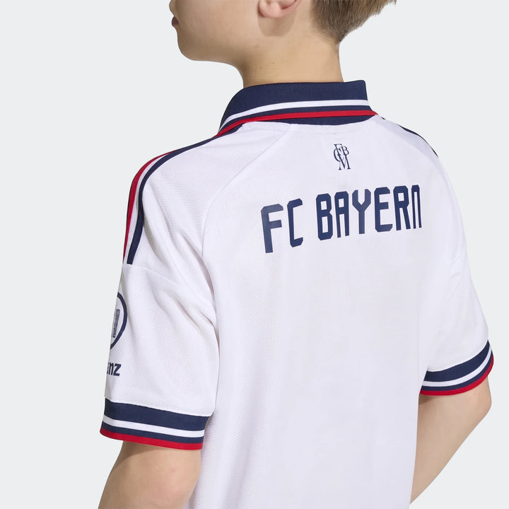 Kids' FC Bayern 26/27 away jersey in white, featuring navy and red striped collar and sleeve cuffs, shown from the back.