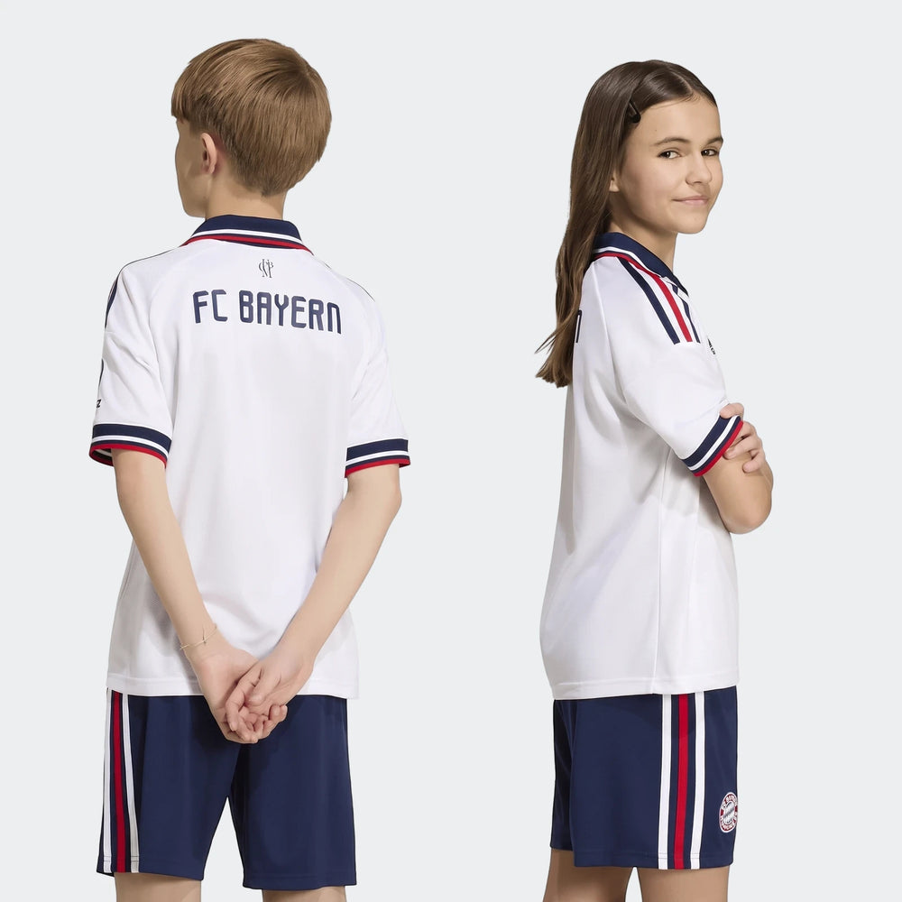 Two children modeling the Fc Bayern 26/27 Away Jersey for kids, featuring a white shirt with navy and red accents, paired