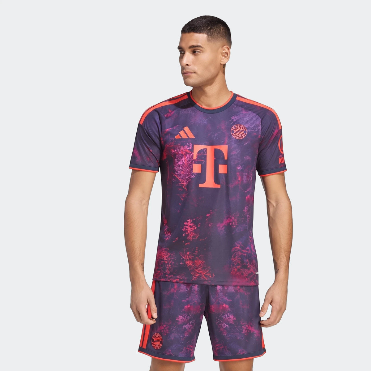 Fc Bayern 26/27 Third Jersey and matching shorts, worn by a male model, featuring a dark purple and pink/red patterned