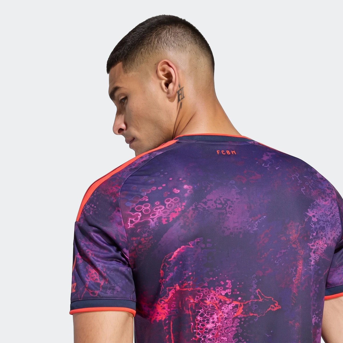 Fc Bayern 26/27 Third Jersey in purple and pink with abstract patterns, featuring orange accents, worn by a man from the