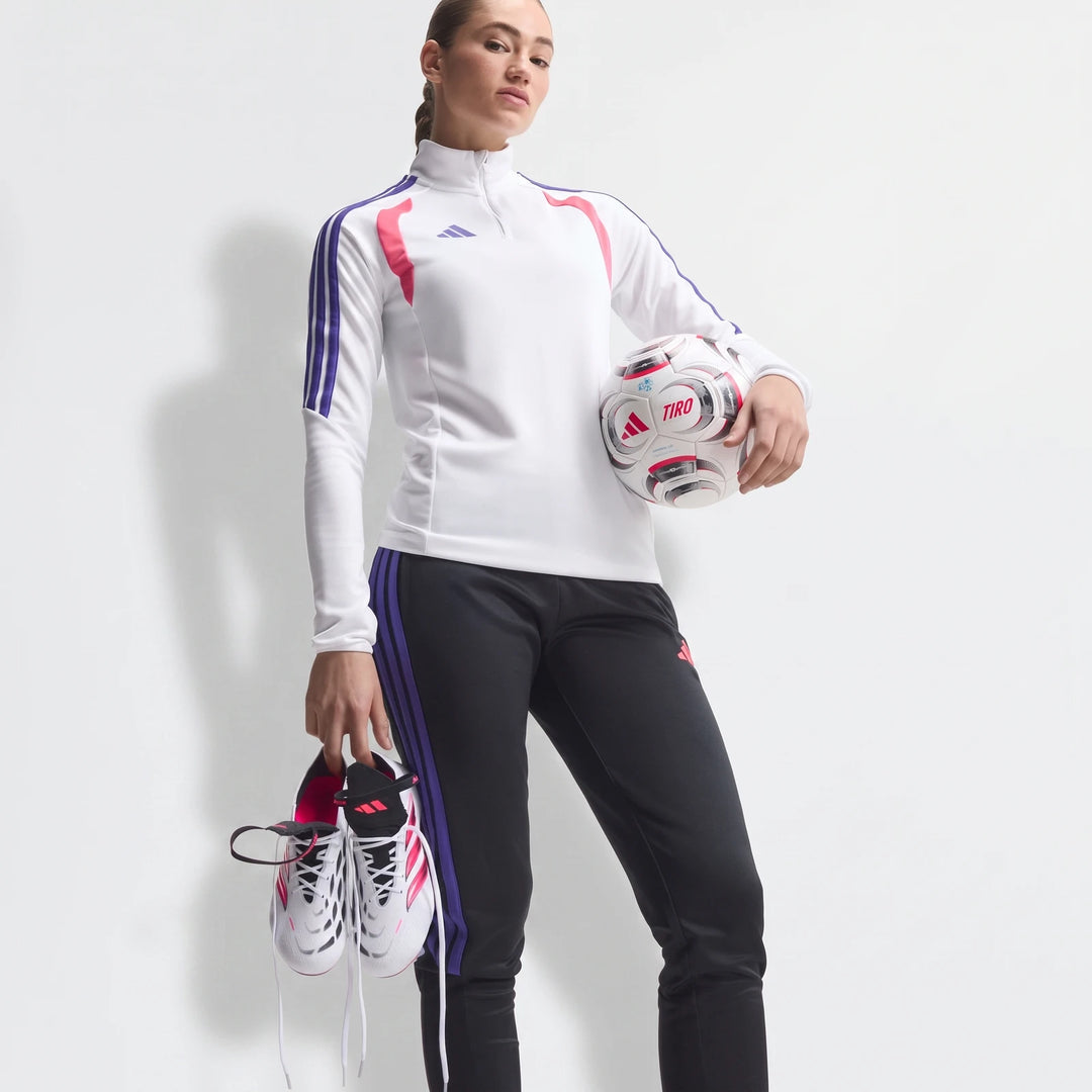 Female model holding white and pink Predator Elite Fold-Over Tongue Firm Ground Football Boots and a soccer ball, wearing a