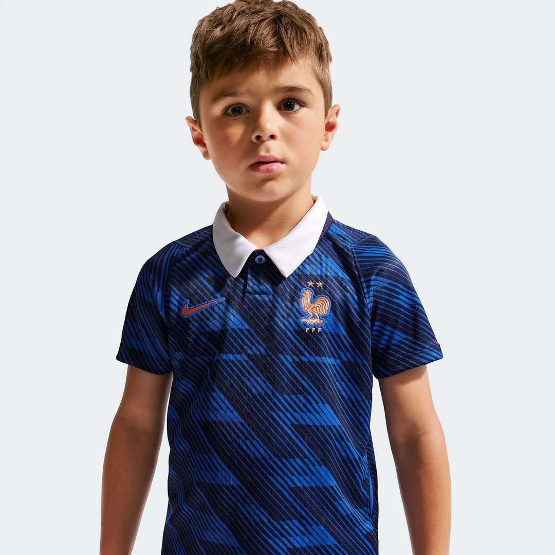 Young boy wearing a blue and black striped Nike FFF 2026 Stadium Home Little Kids' soccer replica jersey, front view.