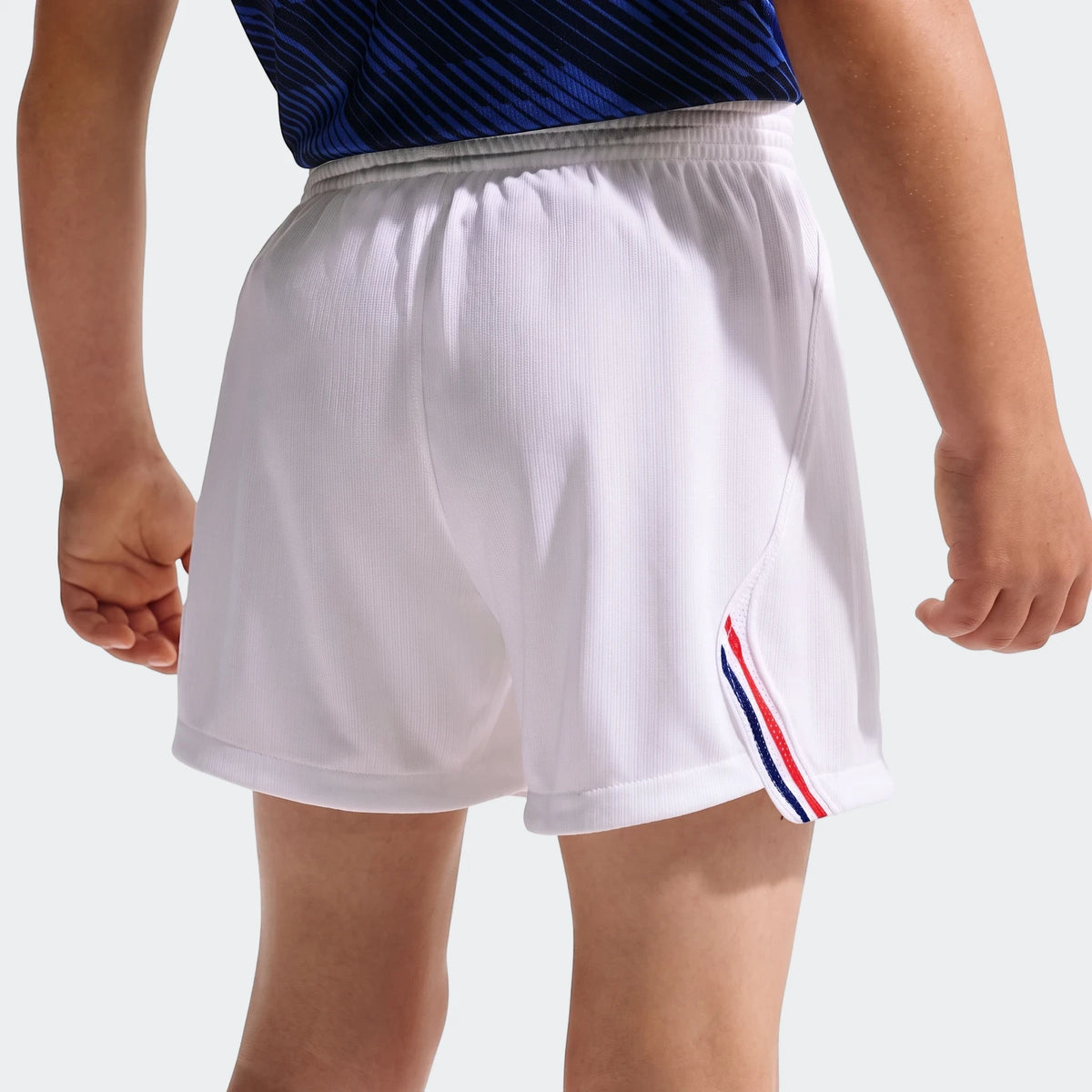 Back view of a child wearing white Fff 2026 Stadium Home Little Kids' Nike soccer replica shorts with blue, red, and white