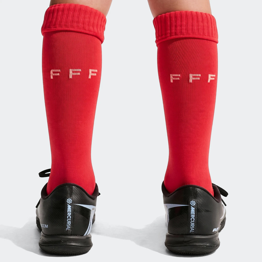 Back view of a child's legs wearing red FFF 2026 Stadium Home soccer socks and black Nike Mercurial soccer cleats.