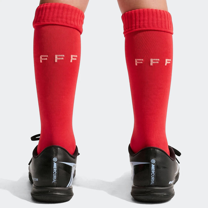 Back view of a child's legs wearing red FFF 2026 Stadium Home soccer socks and black Nike Mercurial soccer cleats.