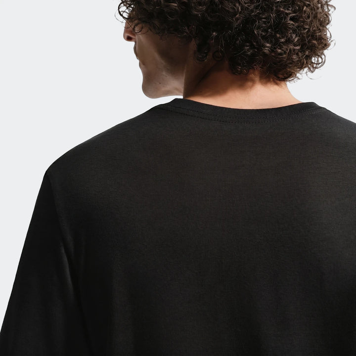 Back view of a man wearing a black Fff men's Nike soccer t-shirt, showcasing the garment's fit and fabric texture from