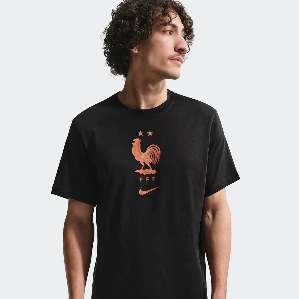 A man wearing a black Nike FFF soccer t-shirt with a copper-colored rooster logo, viewed from the chest up.