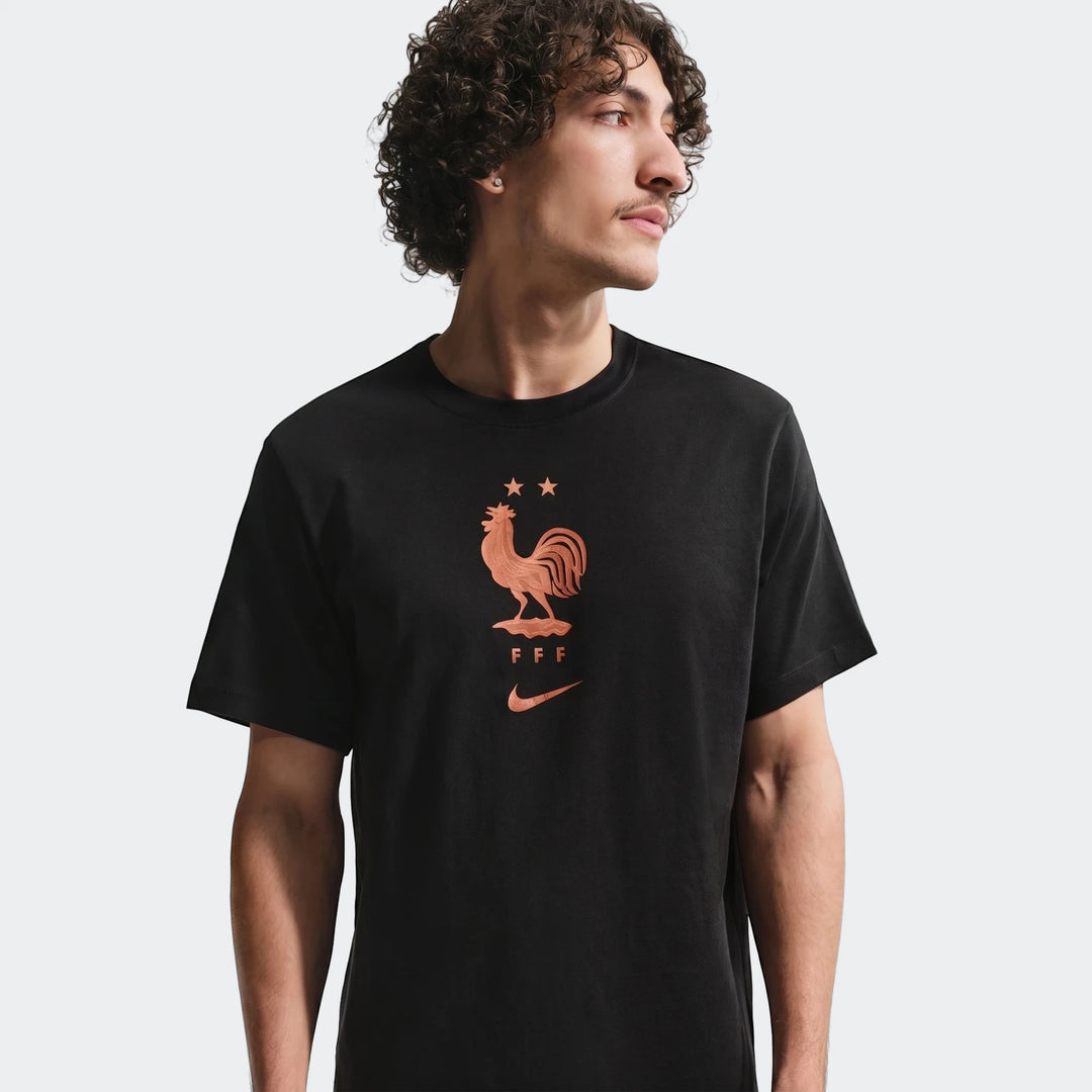 A man wearing a black Nike FFF soccer t-shirt with a copper-colored rooster logo, viewed from the chest up.