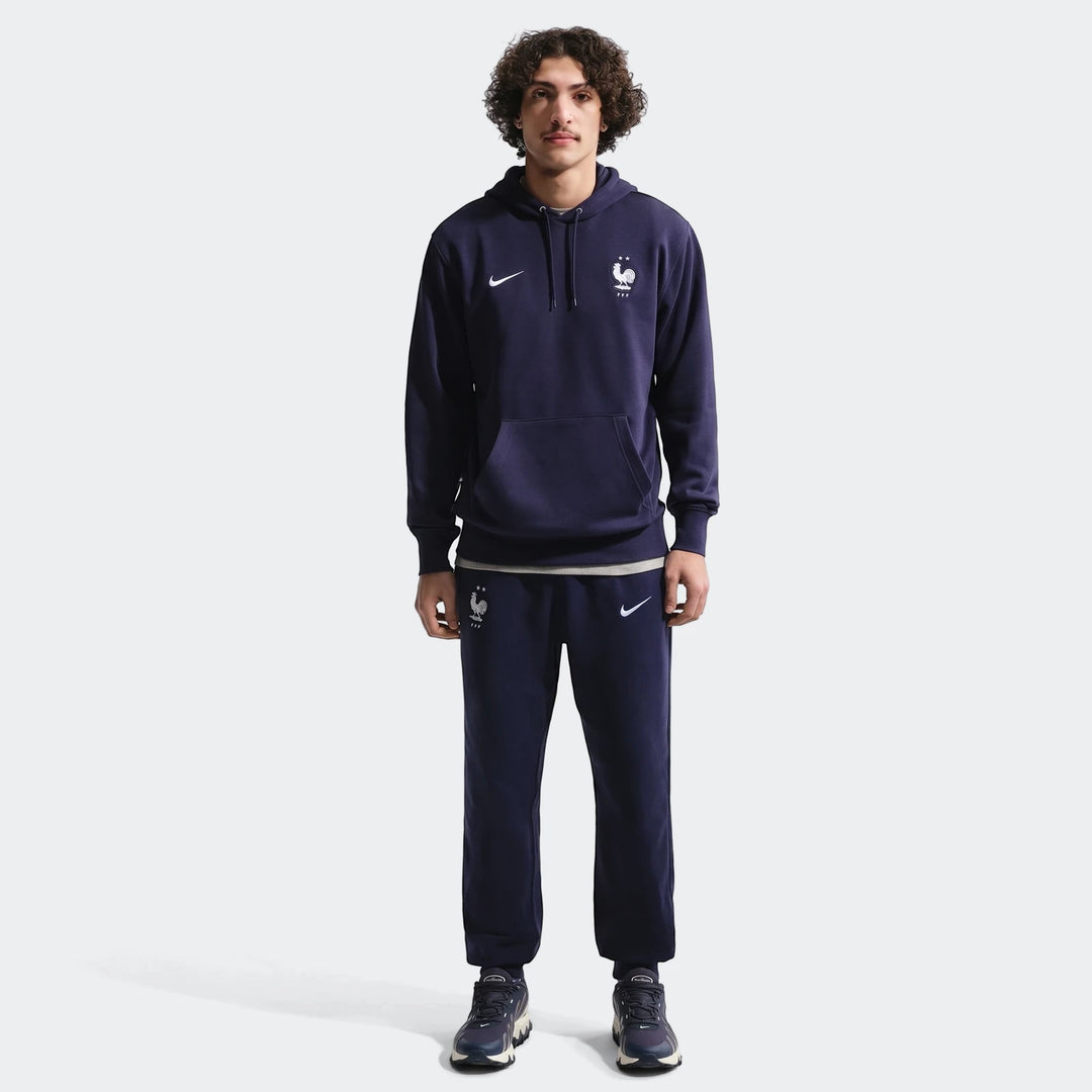 Man wearing Fff Club Blue Men'S Nike Soccer French Terry Joggers and matching hoodie. Full body studio shot.