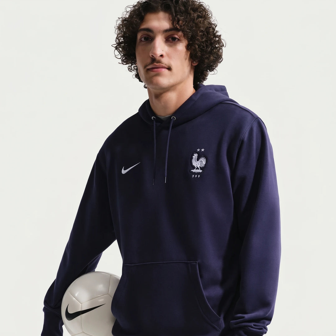 Men's Fff Club Blue Nike Soccer French Terry Pullover Hoodie modeled on a man, showing front view with a soccer ball.