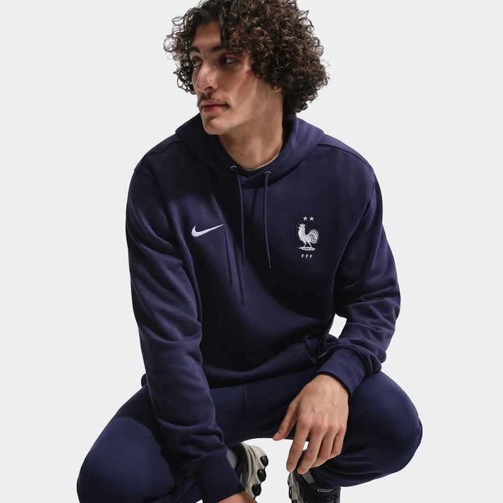 Men's Nike FFF Club French Terry Pullover Hoodie in navy blue, modeled in a squatting pose.