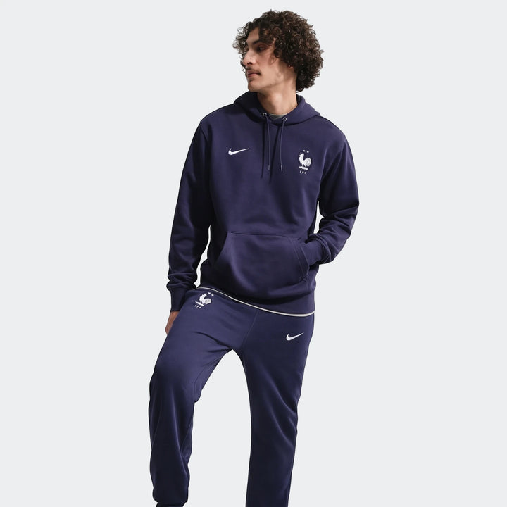 Male model wearing a navy blue Nike FFF Club French Terry tracksuit, featuring a hoodie and joggers, on a light background.