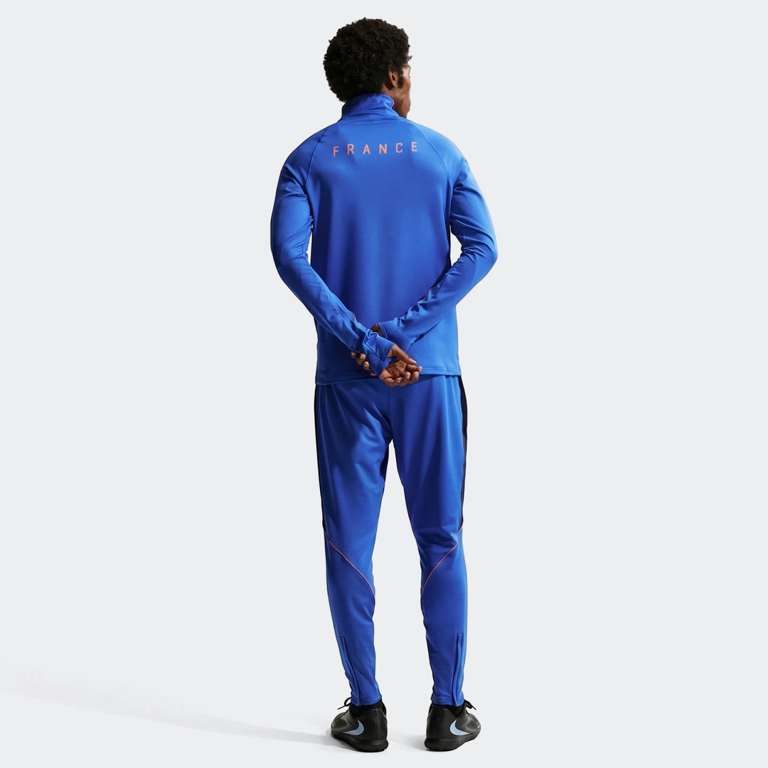 Rear view of a male model wearing a blue FFF Strike Nike Dri-Fit soccer drill top and matching pants with 'FRANCE' text on