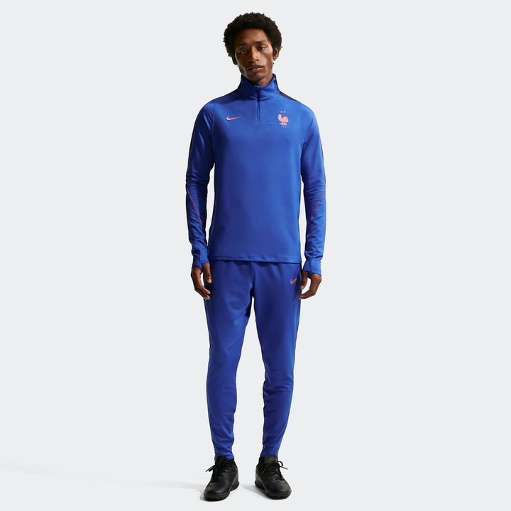 Full body view of a man wearing the Fff Strike Blue Men's Nike Dri-Fit Soccer Drill Top and matching track pants, designed